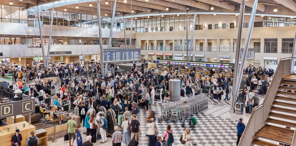 Travlhed ved check-in i Billund Lufthavn med mange rejsende og bagage.